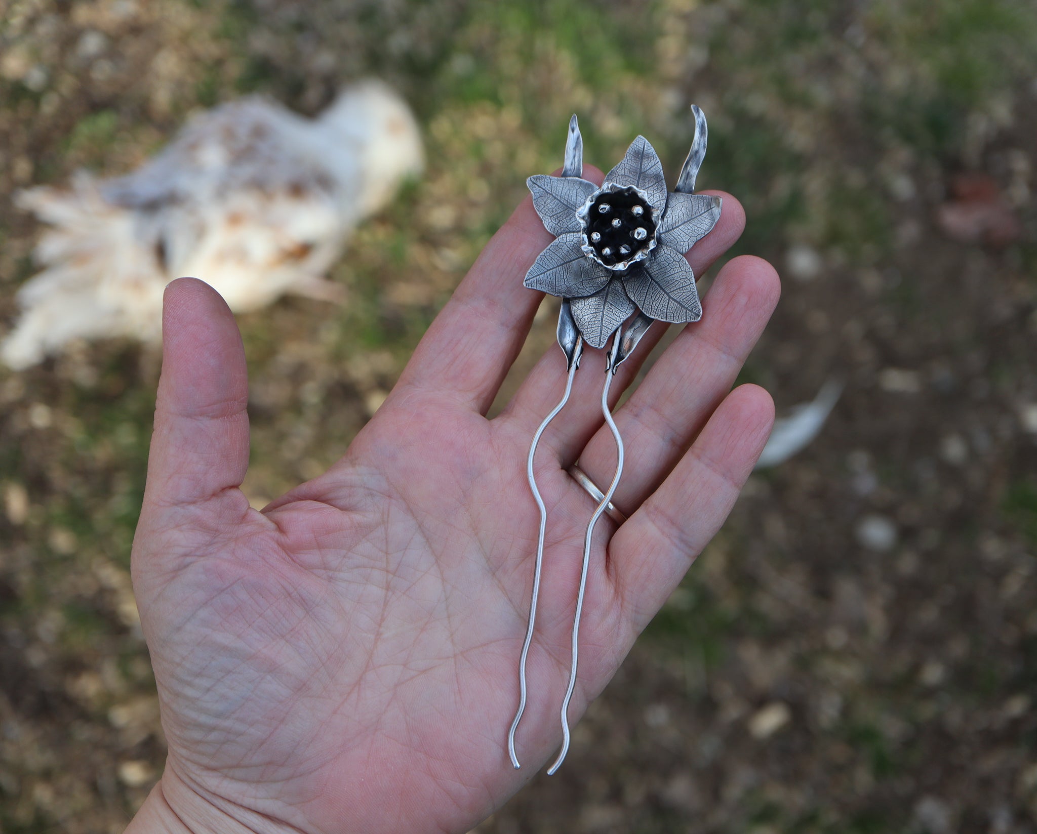 A hand is shown holding the daffodil hair pick to show the size difference. 