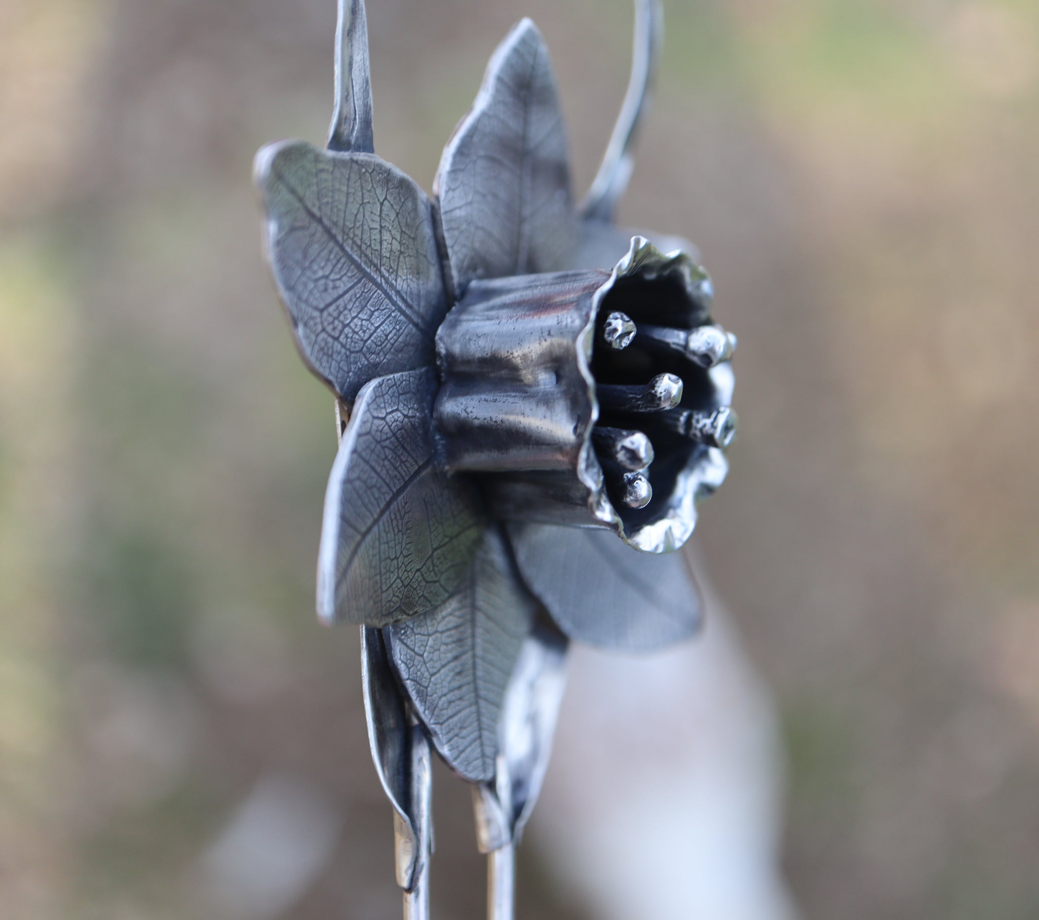 The side view of the handmade daffodil hair pick showing the ruffles in the petals and leaf texture. 