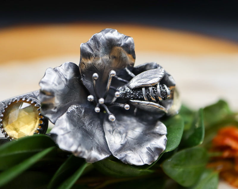 A close up photo of the honey bee and the flower in the center of the bracelet.