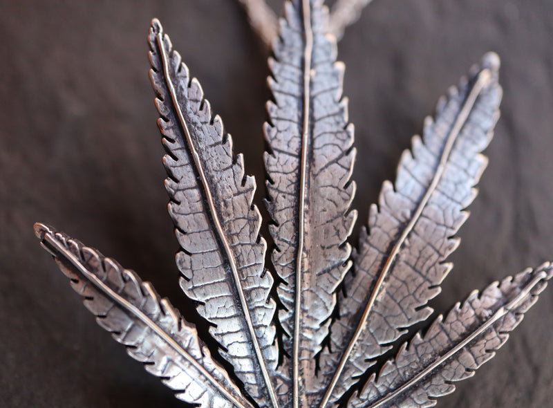 Cannabis leaf close up photo of the handmade sterling silver necklace pendant. 
