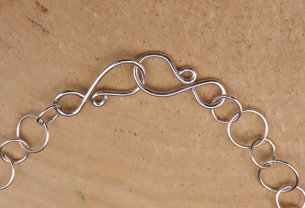 The clasp of the sterling silver necklace showing that the chain is adjustable. 