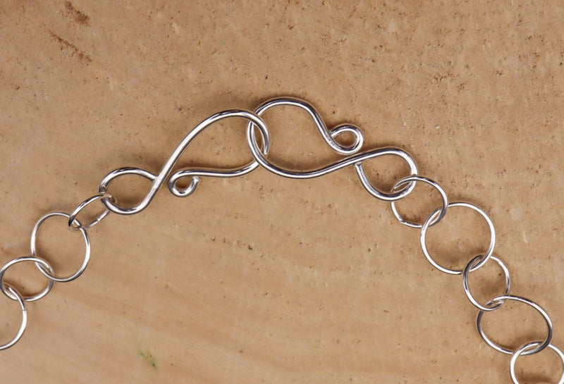 The clasp of the sterling silver necklace showing that the chain is adjustable. 