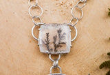 A close up photo of the clear dendritic quartz stone with inclusions that look like real plant material. 