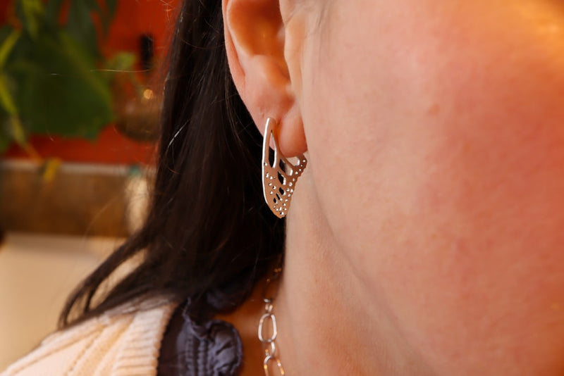 Sterling silver handmade monarch butterfly wing earring studs are being shown worn.