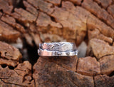A sterling silver mountain ring shown on a piece of light brown wood. 