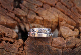 Another side of the White Mountains range ring in sterling silver. It is shown on a piece of brown wood. 