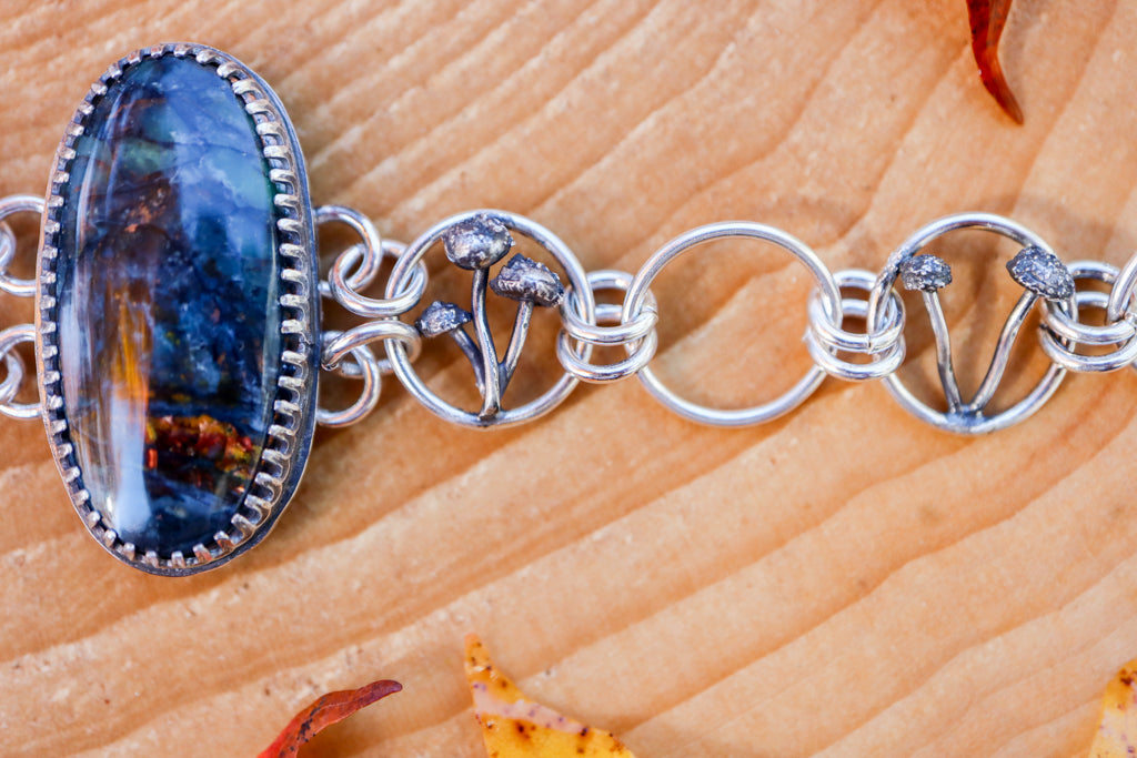 A close up photo of two of the very small links in the bracelet with clusters of silver mushrooms growing within them. 