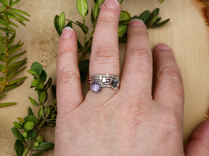 A hand is show wearing all five of the stacking rings together. 