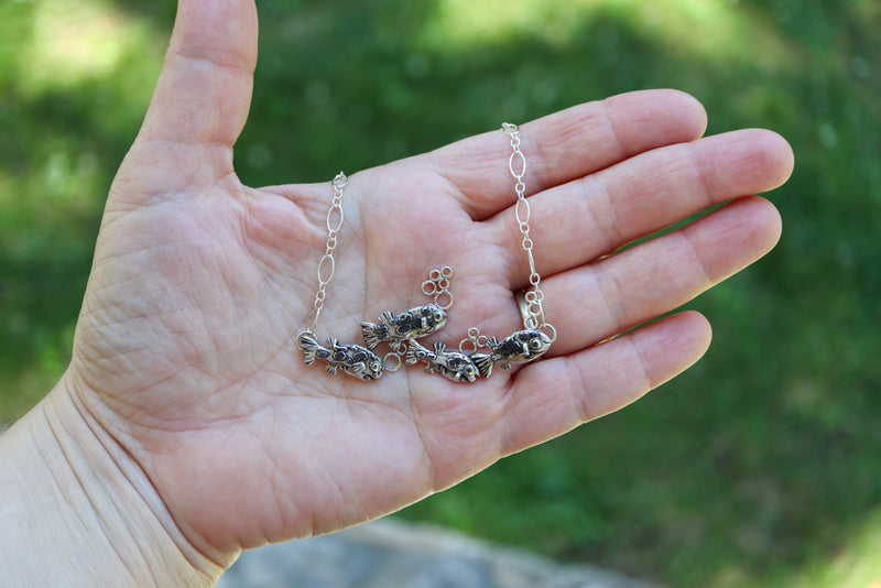 A hand is shown holding the necklace for size. The fish are about 2.25 inches across all together. 
