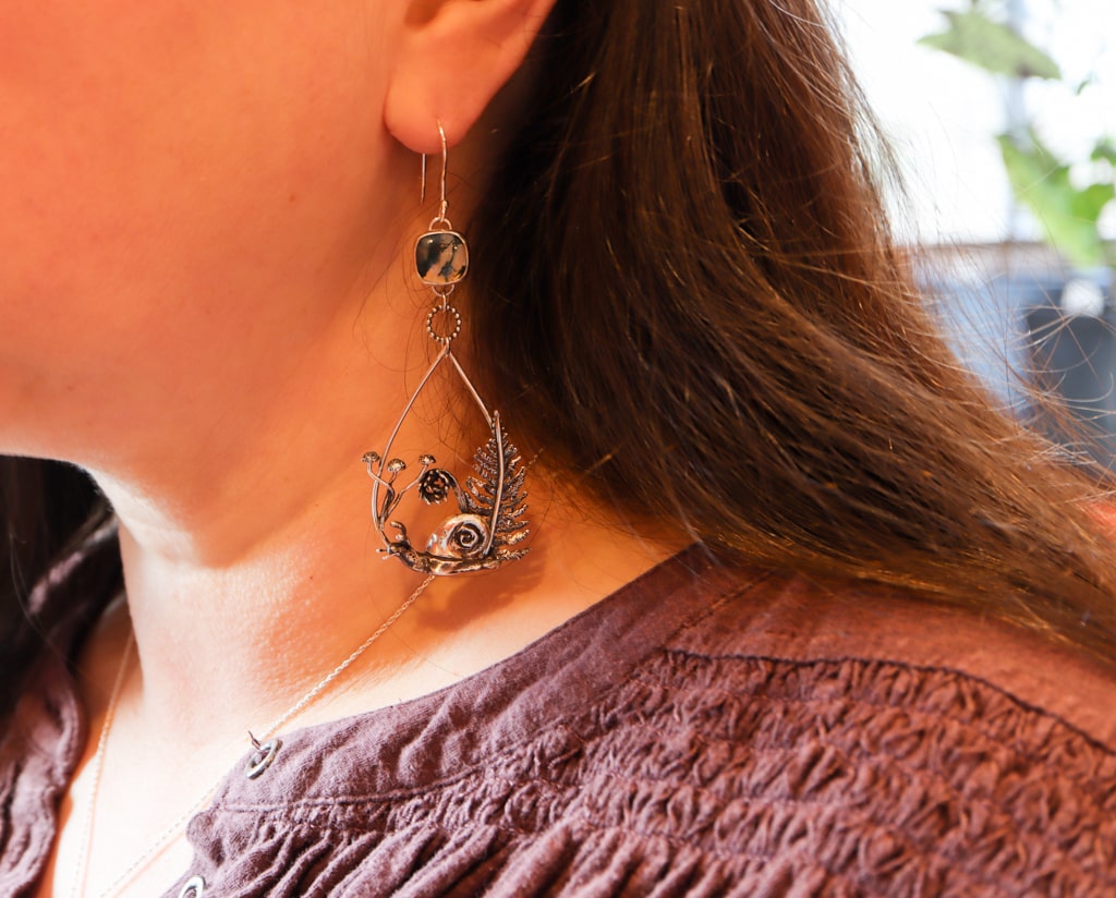 A close up photo of a woman with long dark hair wearing the earrings. 