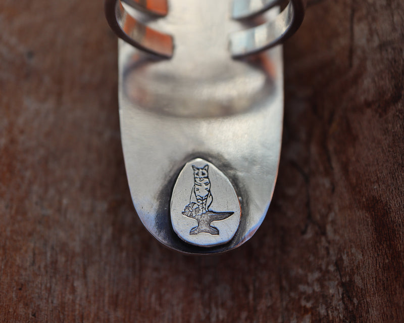 The back of the stag beetle ring shows The Striped Cat Metalworks Maker's Mark. It is of a striped cat sitting on an anvil. 