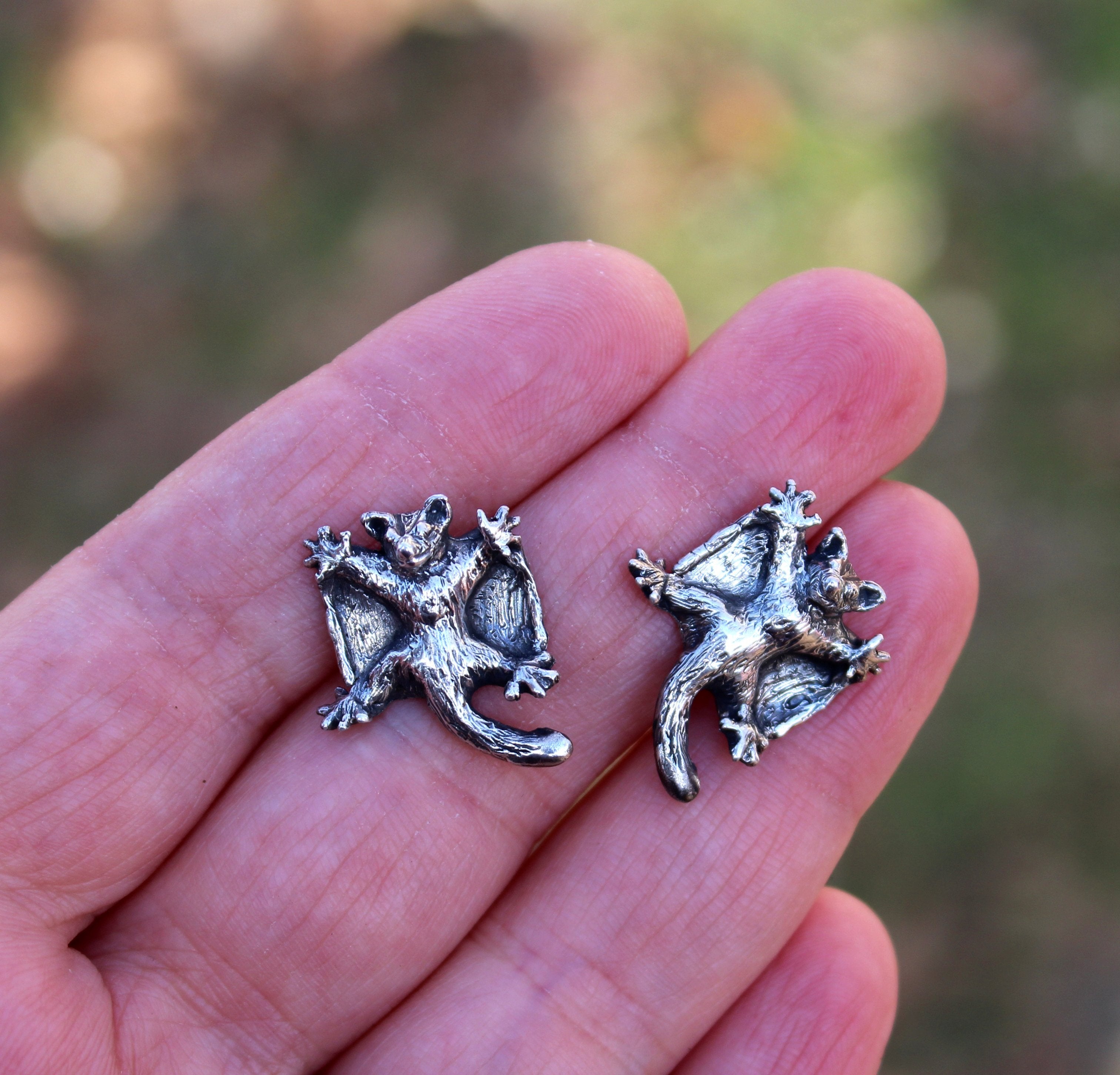 A hand holding the little gliding sugar glider earring studs to show size. 