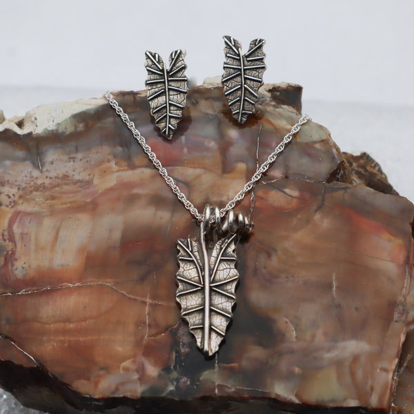 A necklace and earring set of alocasia polly leaves. They are a pair of stud earrings about 1/2 inch tall and a leaf for a necklace that is 3/4 inch tall. 